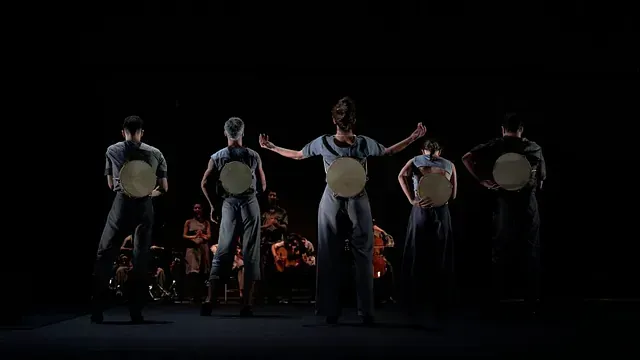 Un grupo de personas está de pie en un escenario sosteniendo tambores.