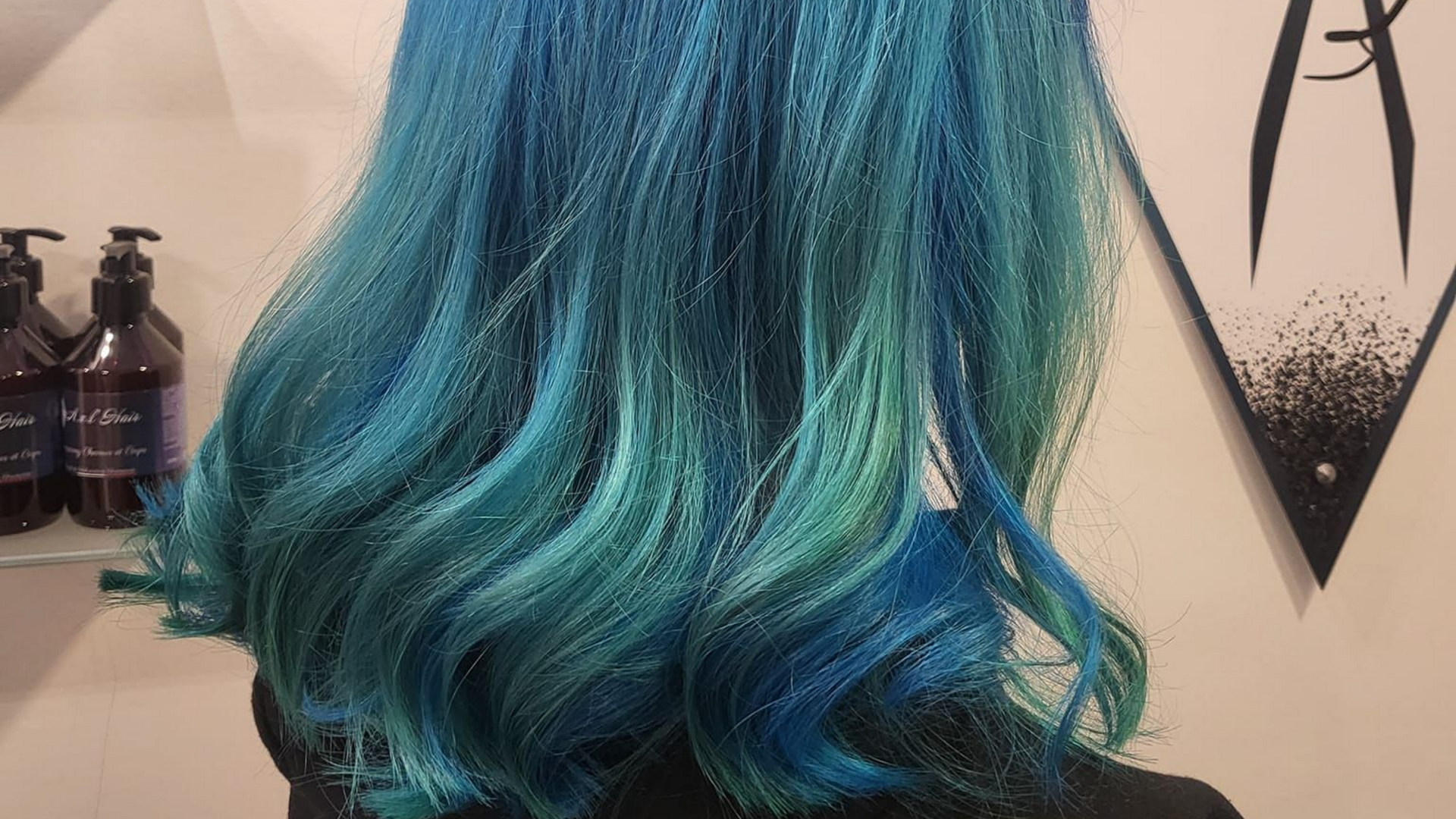 Cheveux d'une femme teints dans des tons bleus et turquoise, avec un effet dégradé.