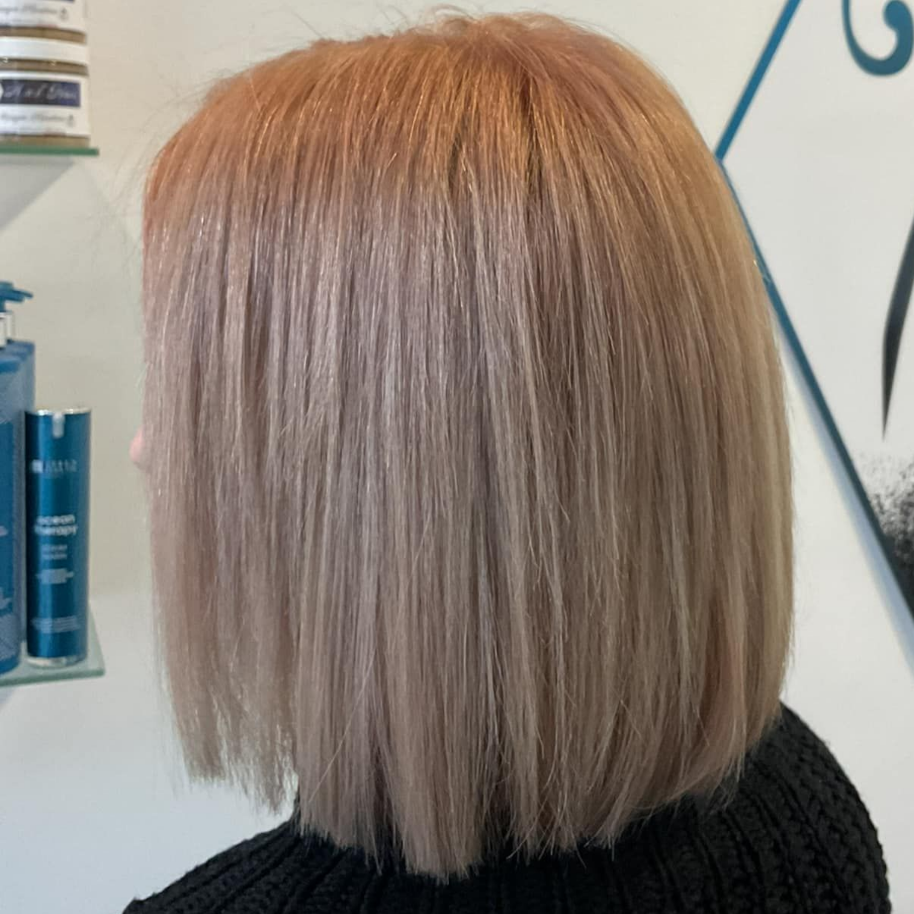 Femme aux cheveux coupés au carré, châtain clair avec de subtiles nuances roses, debout à l'intérieur.