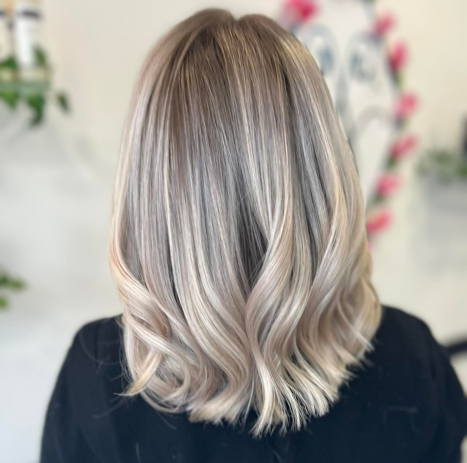 Cheveux blonds avec des mèches et des ondulations souples, vus de dos.