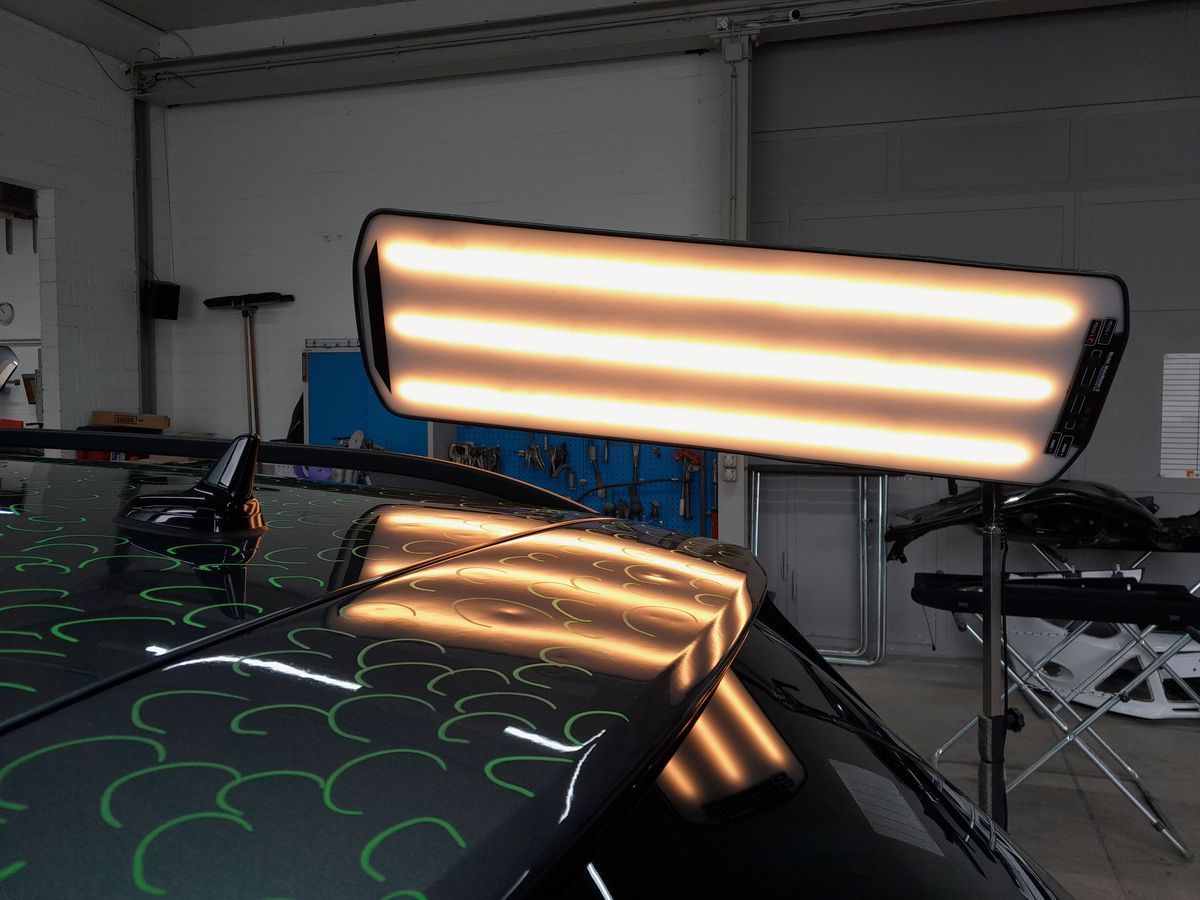 Heck eines blauen BMW mit sichtbaren Stossstangenschäden und Auspuffrohren in einer Garage