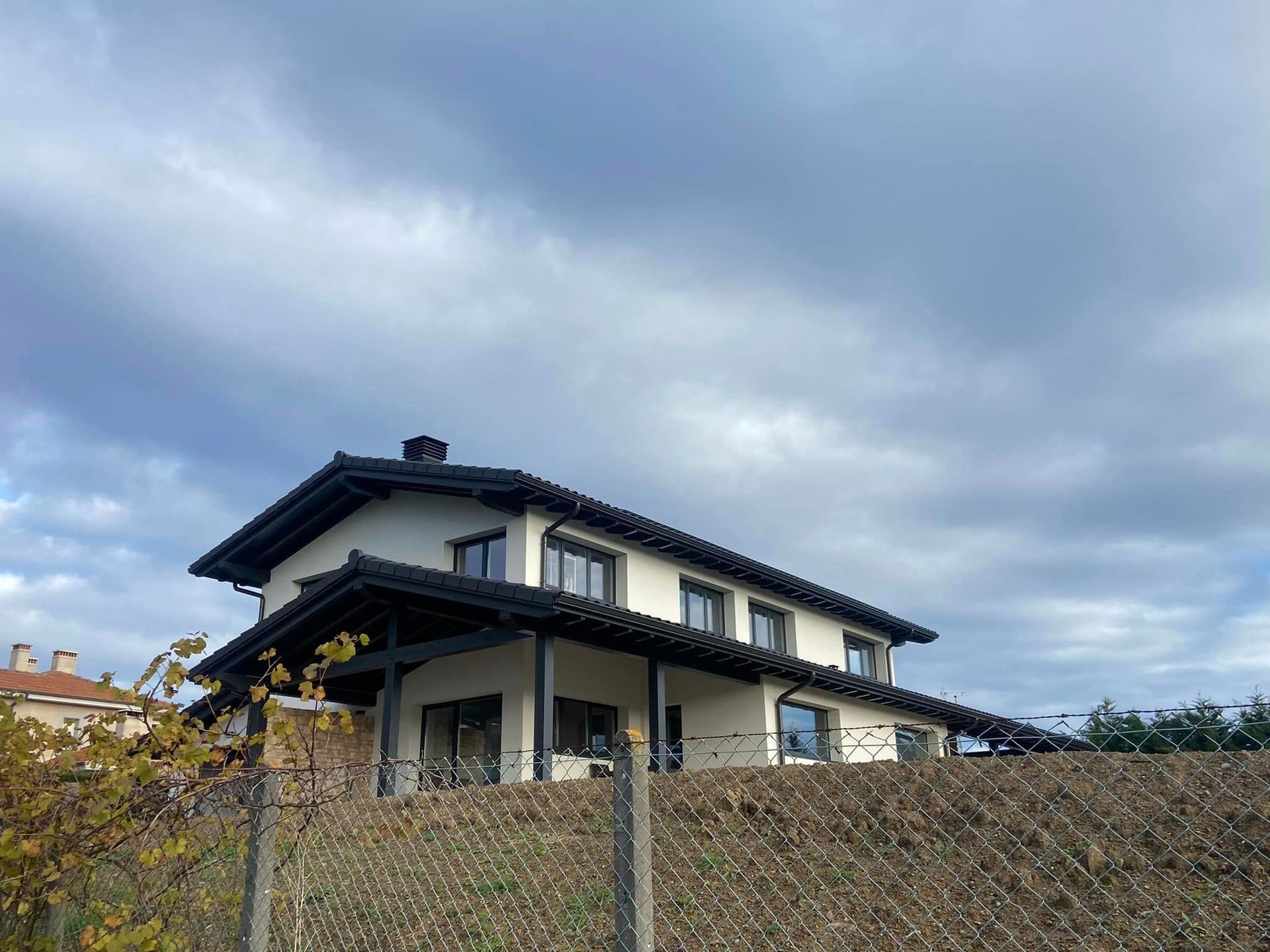 Una casa está situada en la cima de una colina con una valla delante de ella.