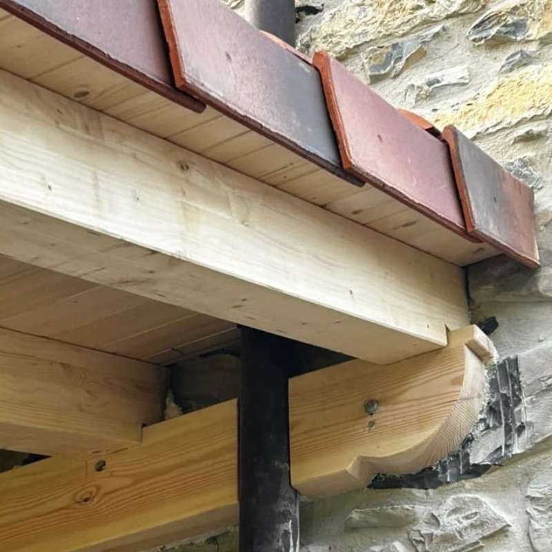 Una viga de madera está fijada a una pared de piedra.