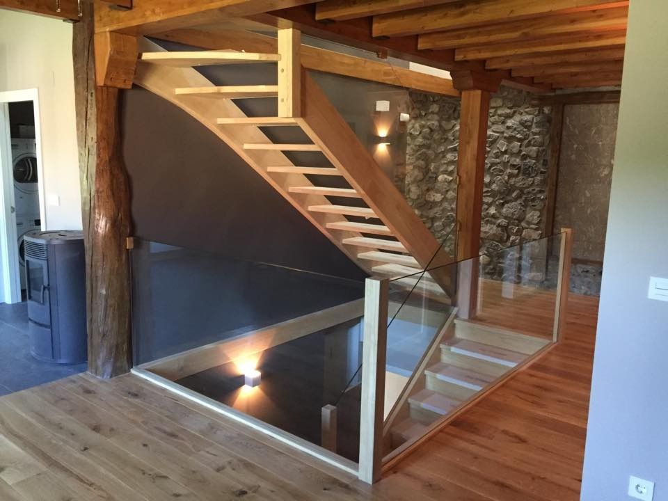 Una escalera de madera con barandilla de vidrio en una casa.