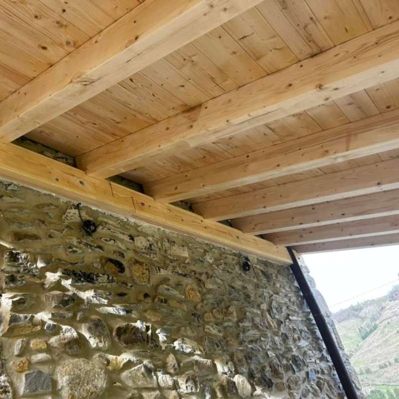 Un muro de piedra con un techo de madera encima