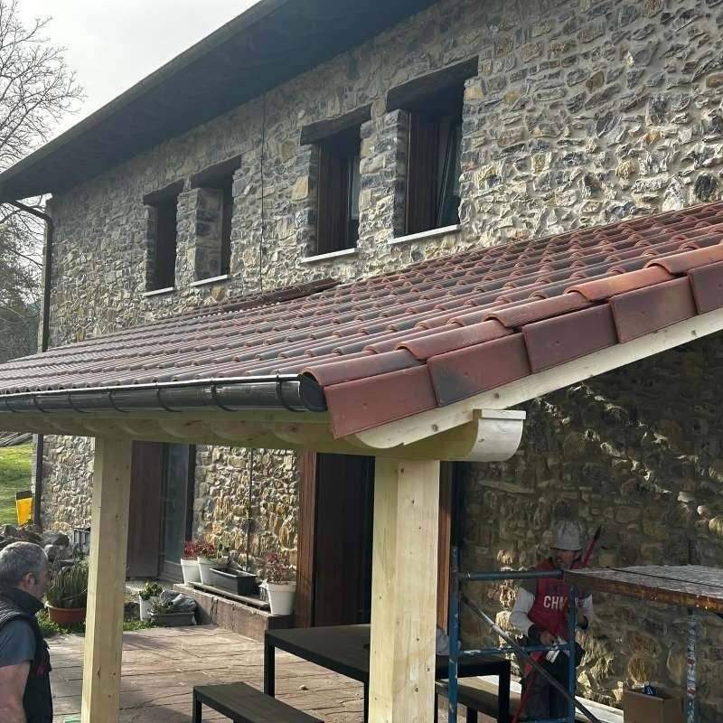 Un hombre está de pie bajo un porche cubierto frente a un edificio de piedra.