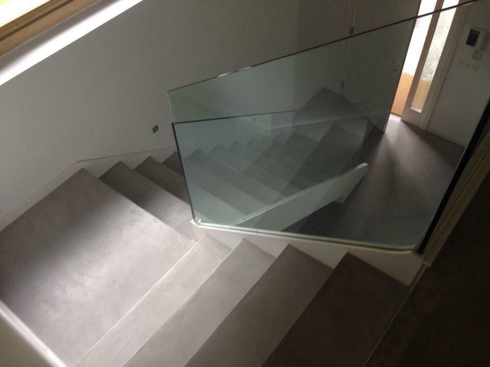 Una escalera con barandilla de cristal que sube al segundo piso.