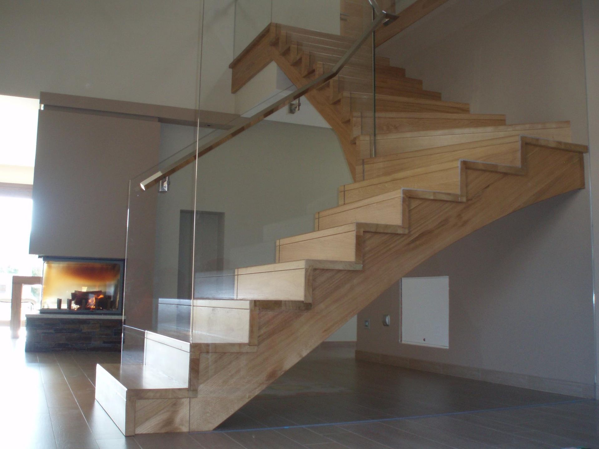 Una escalera de madera con barandilla de vidrio en una sala de estar.