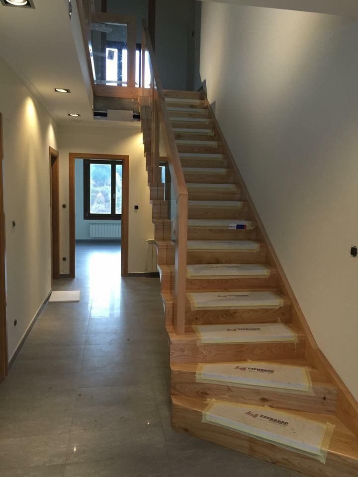 Un pasillo con una escalera de madera que conduce al segundo piso.