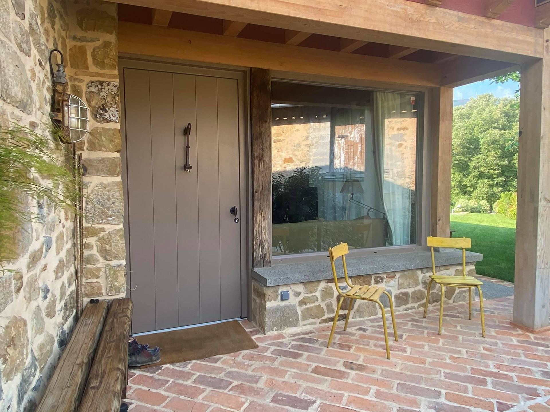 Un porche de ladrillo con sillas y un banco frente a un edificio de piedra.