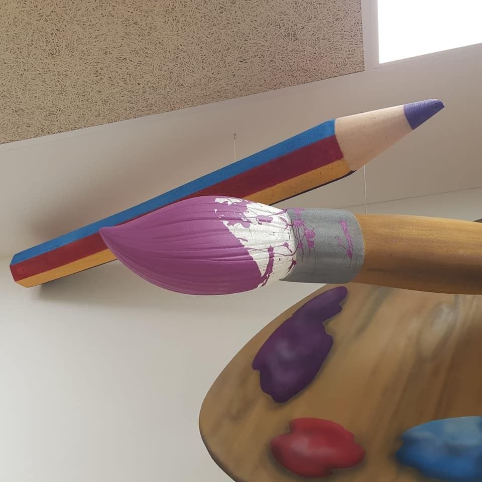 Un pincel está pintado de morado al lado de un lápiz.