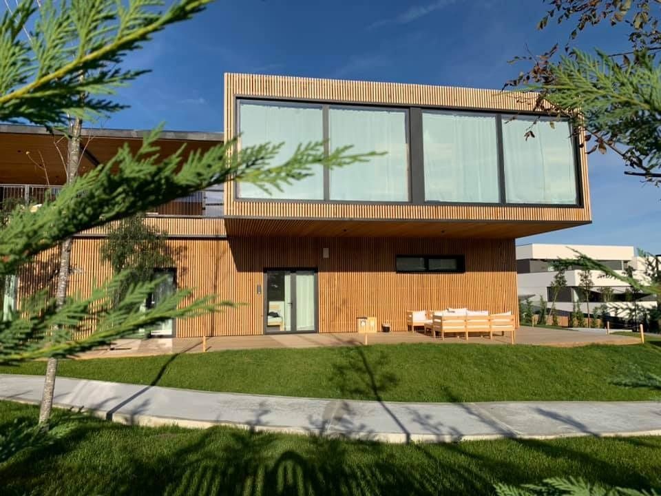 Una casa grande con muchas ventanas está rodeada de árboles.