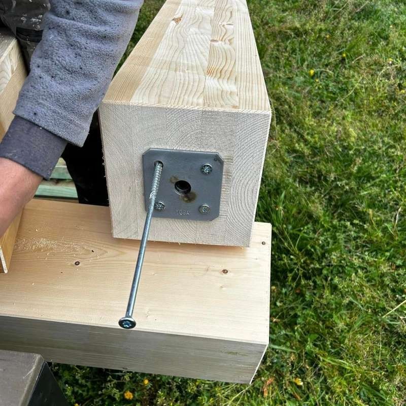 Una persona sostiene un trozo de madera con un tornillo en él.