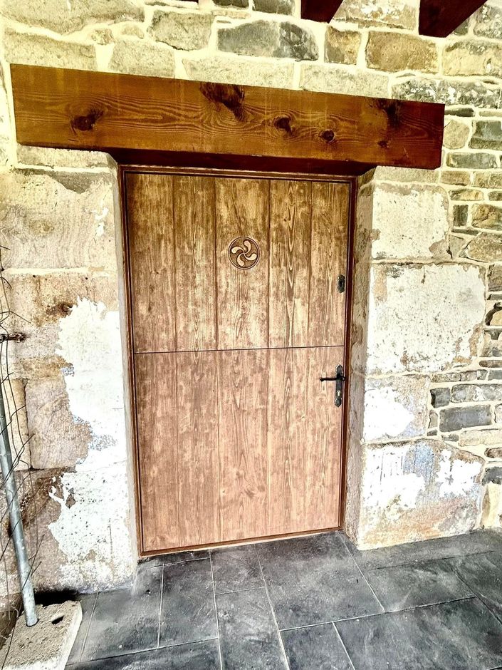 Hay una puerta de madera en el medio de una pared de piedra.