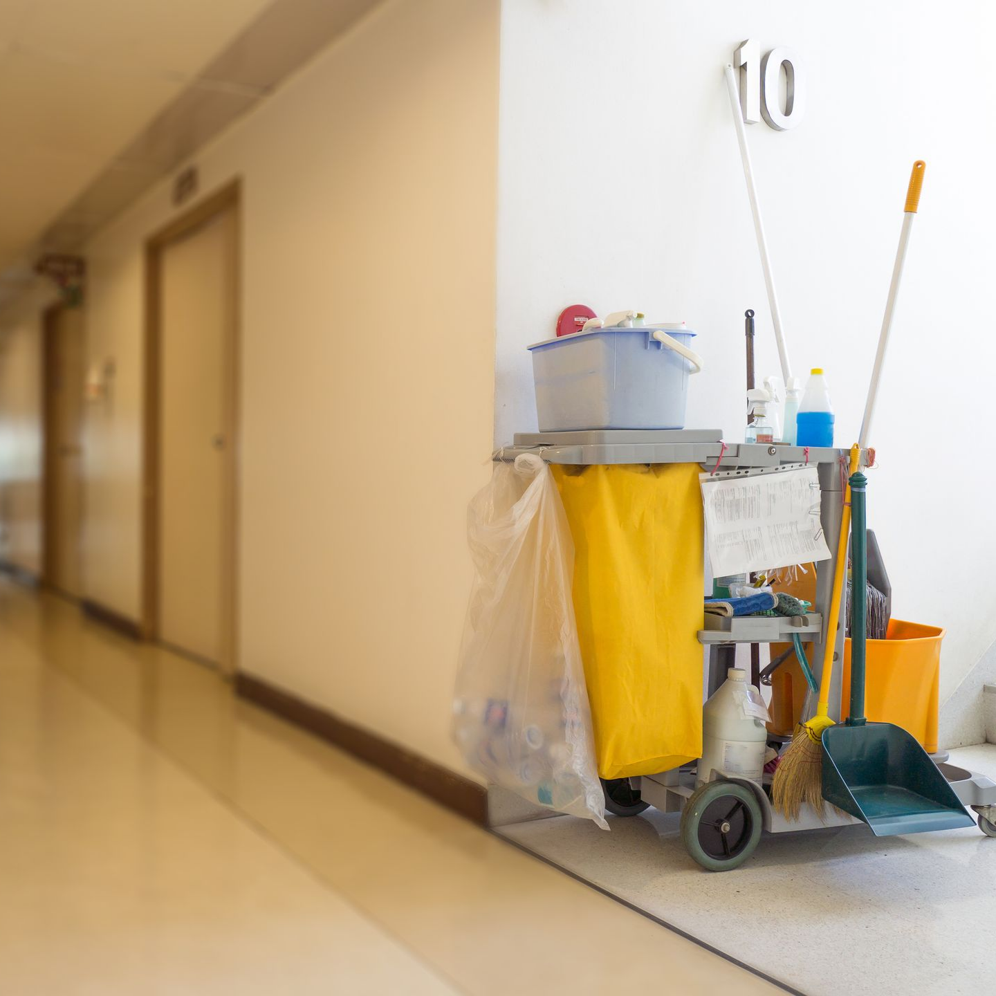 Chariot de nettoyage dans un couloir, contenant des produits de nettoyage et un balai.