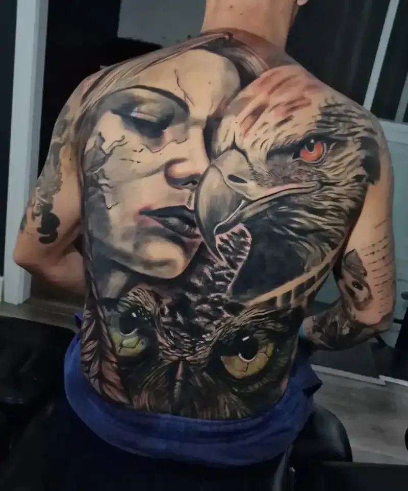 Tatuaje detallado en la espalda: rostro de mujer, águila y búho con sombreado realista, ambientado en interiores.