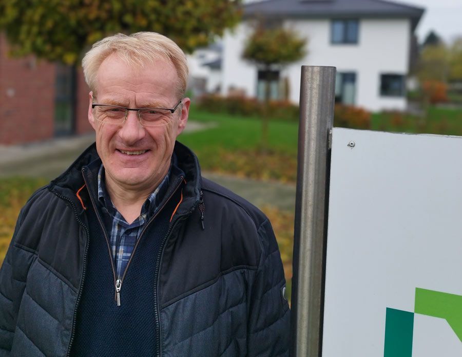 Ein Mann in einem blauen Hemd lehnt an einem Schild mit dem Buchstaben n darauf