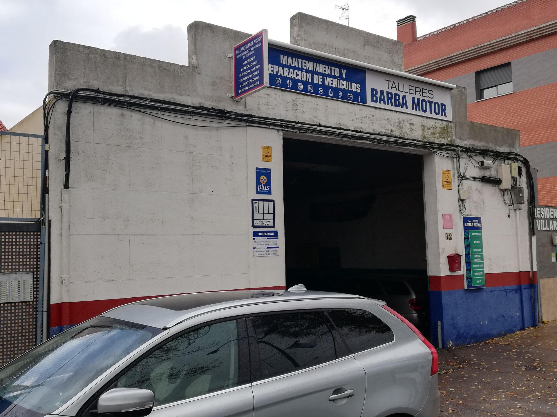 Un coche está aparcado delante de un edificio que dice Barba Motor.