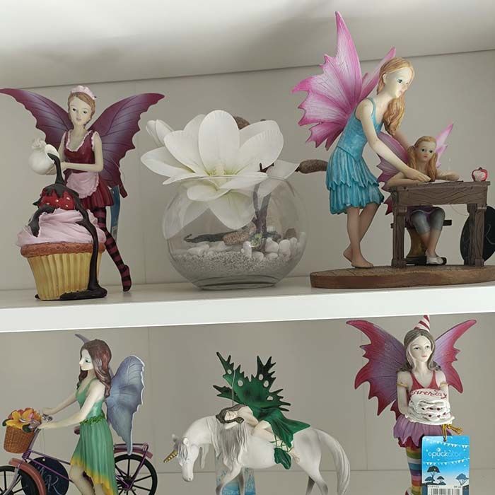 Un estante lleno de figuras, incluida una hada montando en bicicleta.