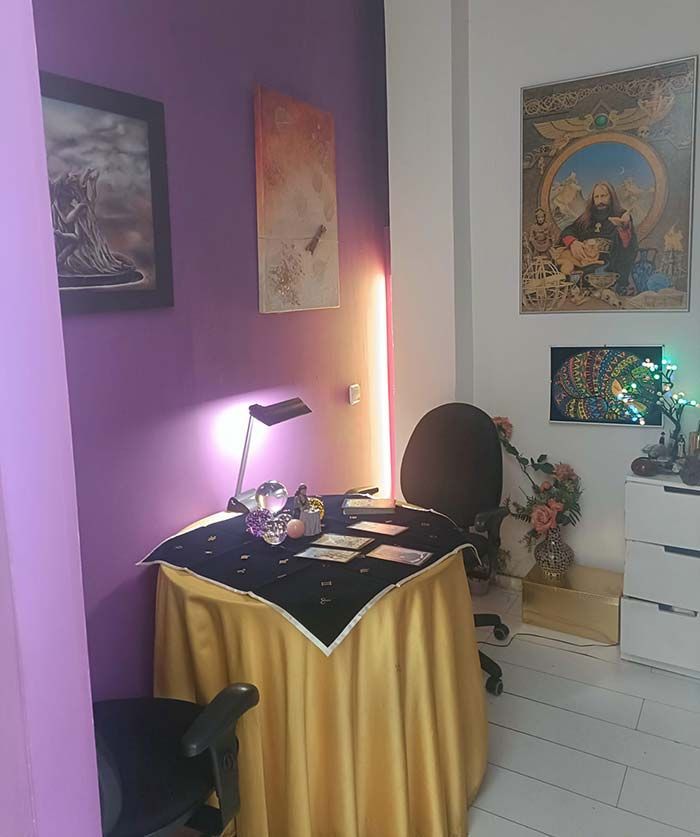 Una habitación con paredes moradas y una mesa con una falda dorada.
