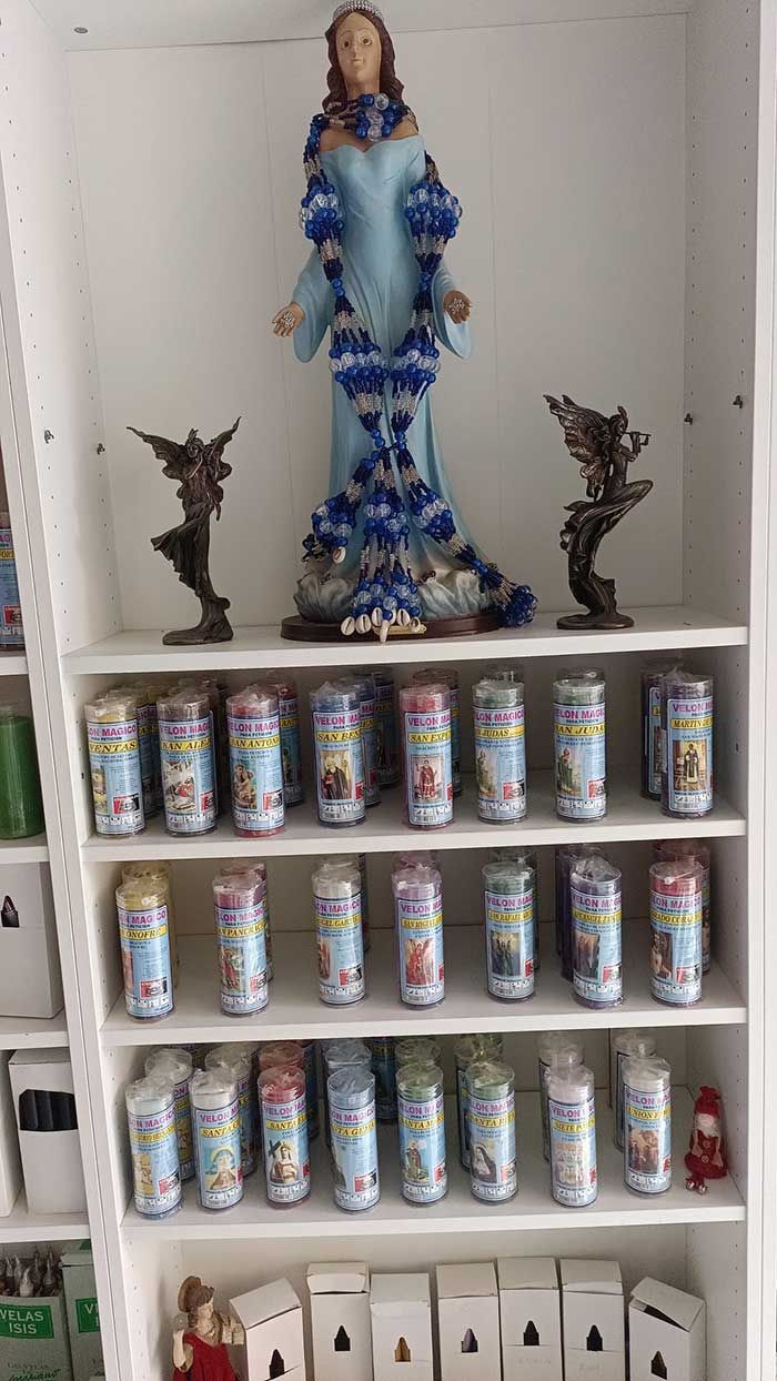 Un estante lleno de velas y una estatua de una mujer.