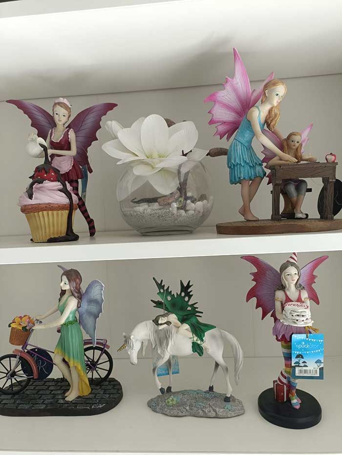 Un estante lleno de figuras, incluida una hada montando en bicicleta.
