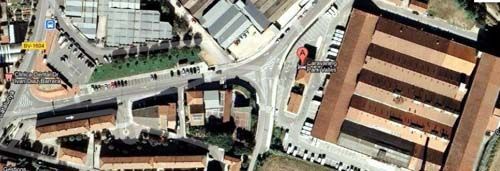 Vista aérea de una intersección de la ciudad con calles, edificios y estacionamientos. Se ve un marcador rojo.