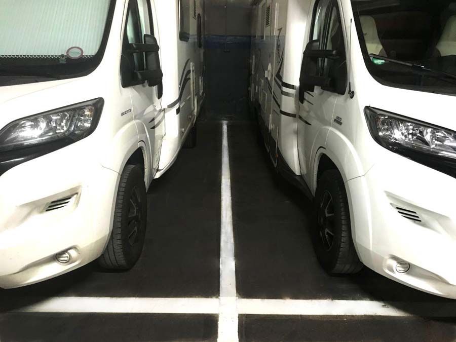 Dos autocaravanas blancas estacionadas en un espacio de estacionamiento marcado.