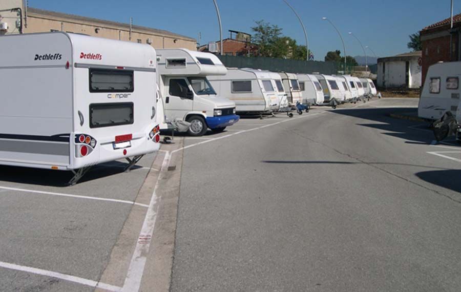 Autocaravanas y vehículos recreativos estacionados en un estacionamiento bajo un cielo brillante y soleado.