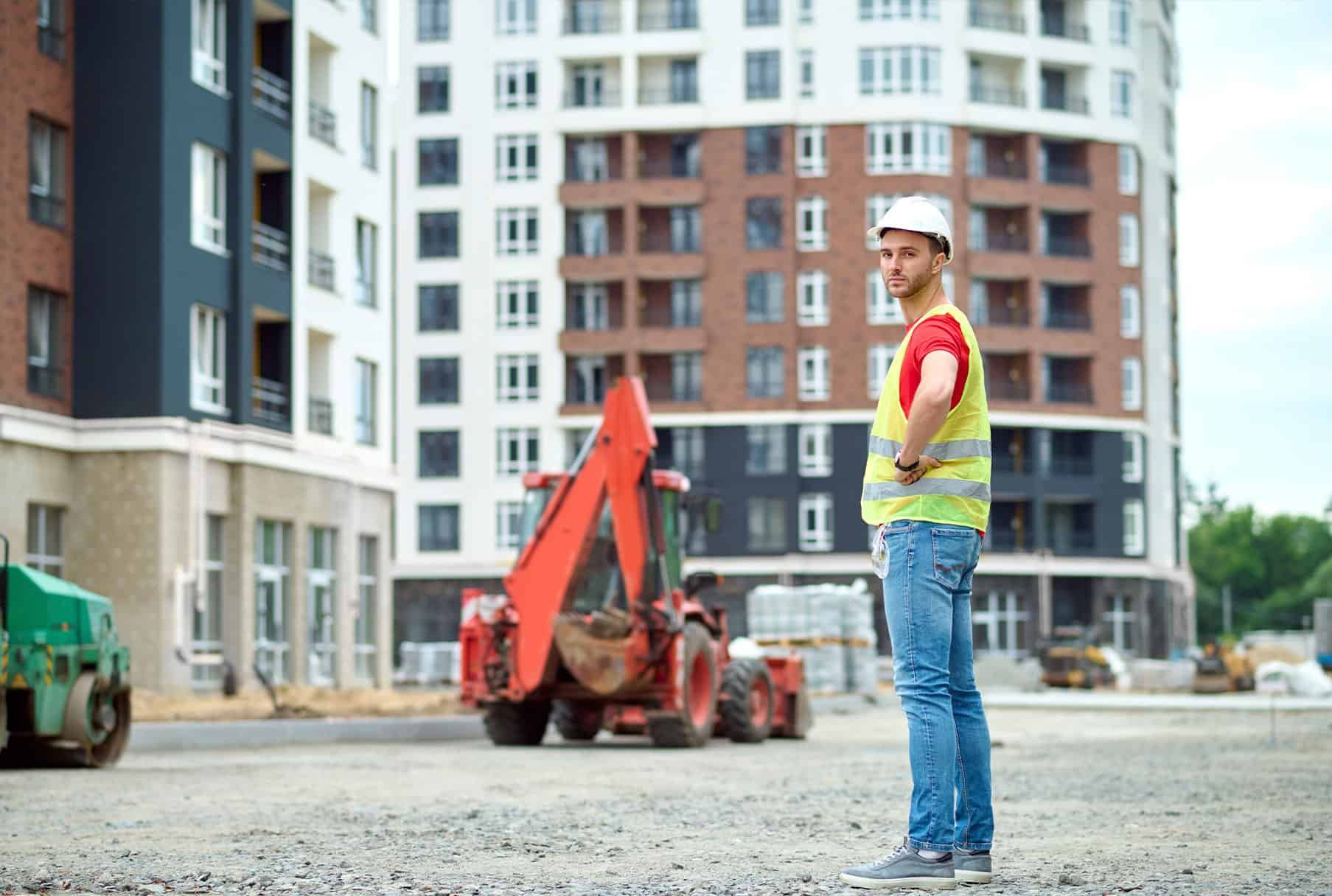 Moderni valkoinen talo mustilla yksityiskohdilla ja puisella terassilla, sininen taivas yläpuolella.
