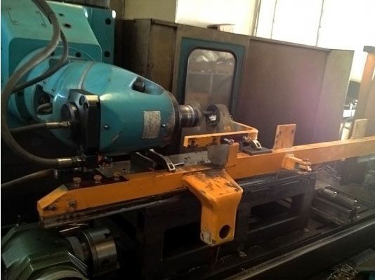 Una máquina industrial azul y naranja, posiblemente una amoladora, en un taller.