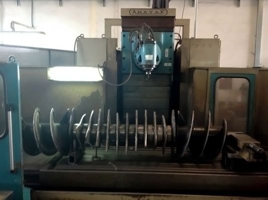 Pieza espiral de metal delante de una fresadora.