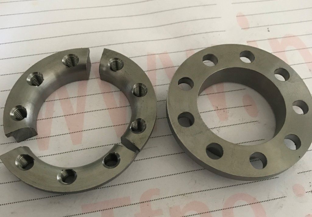 Dos anillos de metal; uno dividido en dos partes, ambas con agujeros para pernos.