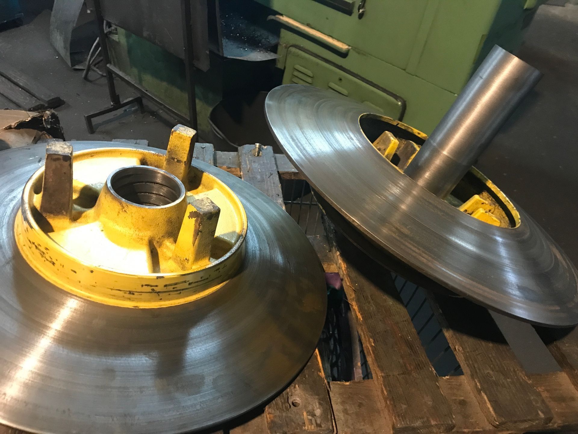 Dos grandes piezas de máquina de metal, una encima de la otra, sobre una superficie de madera.