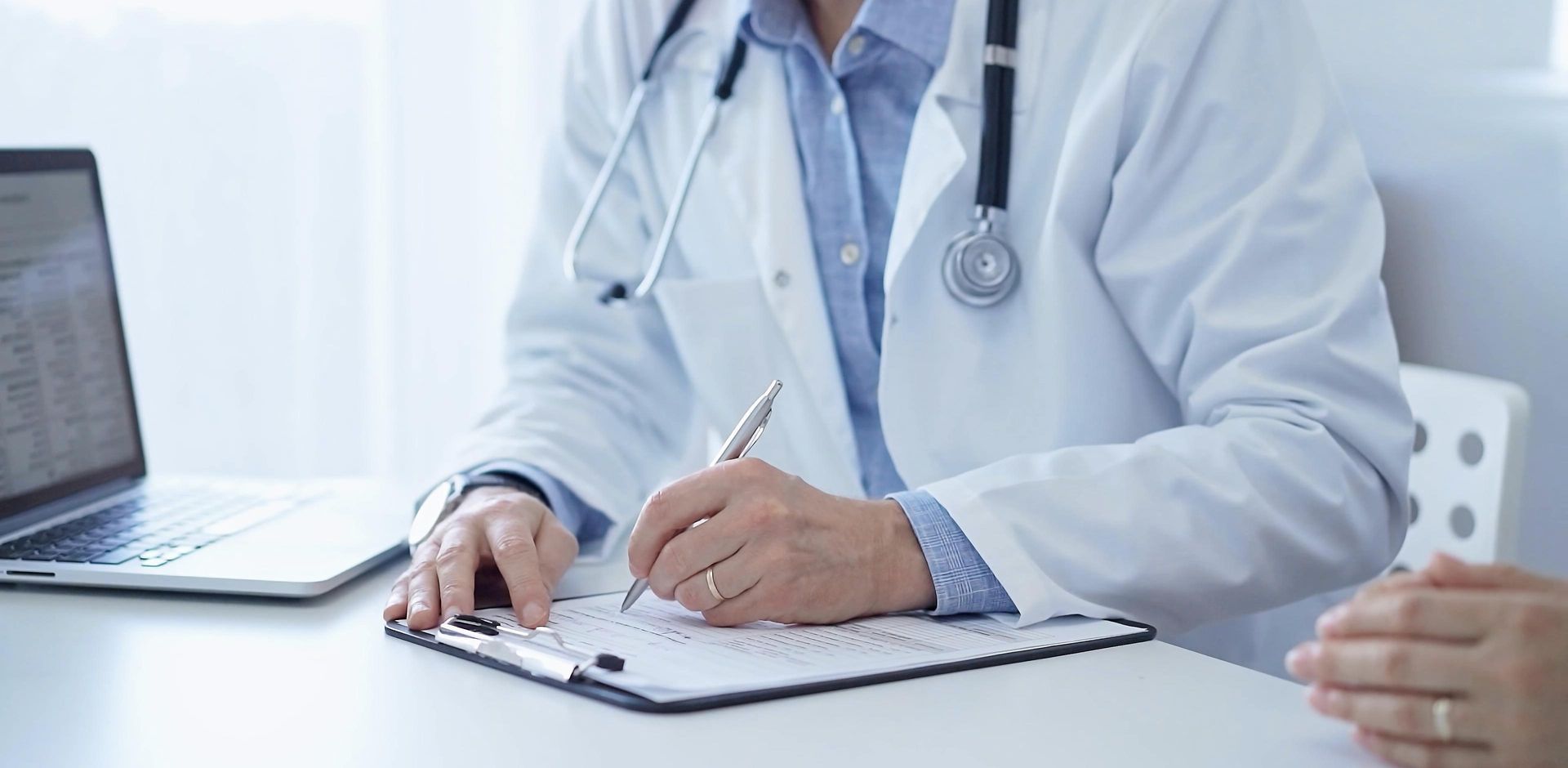 Un medico è seduto alla scrivania e scrive su una lavagna.