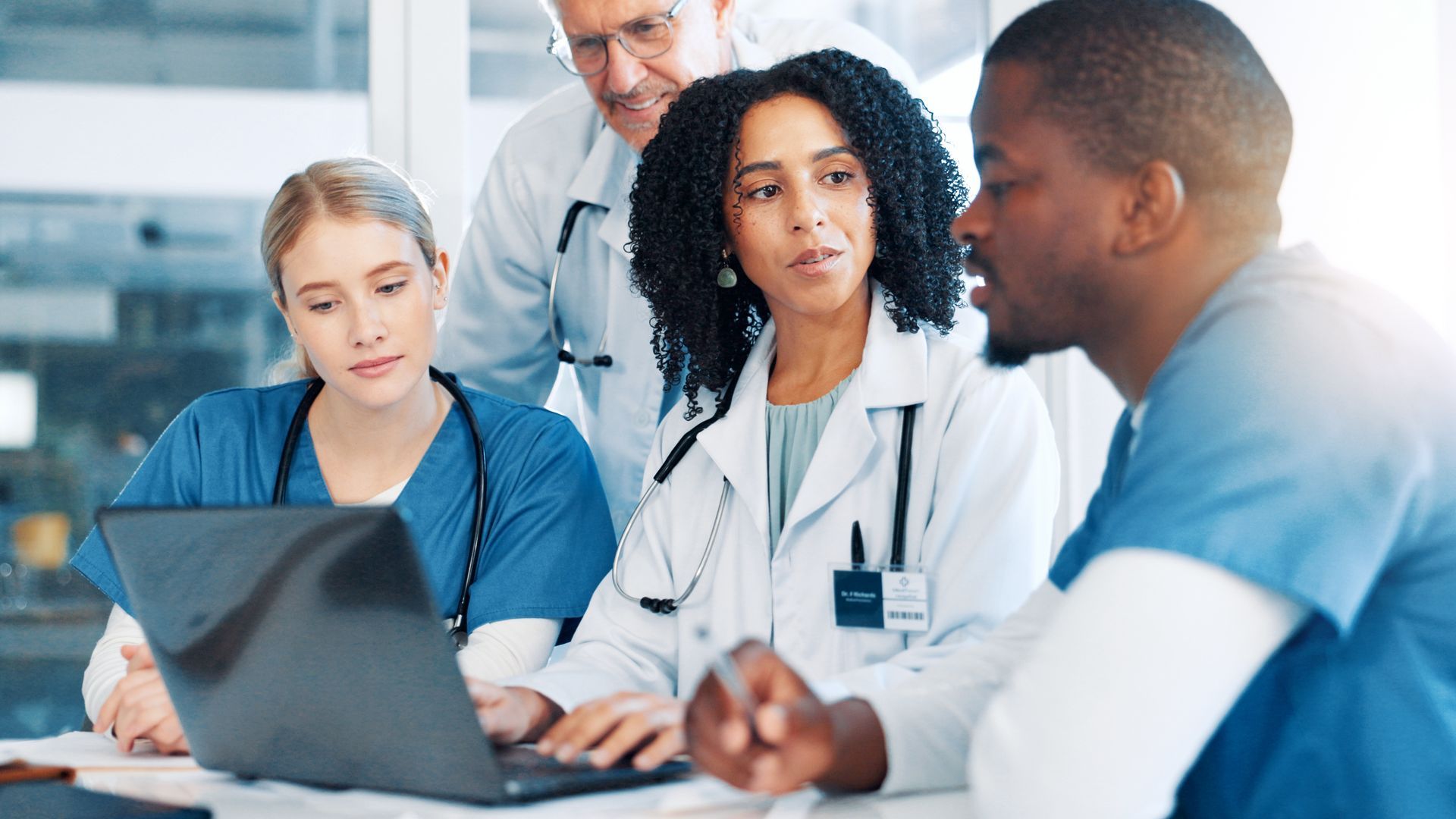 Un gruppo di medici e infermieri sta guardando un computer portatile.