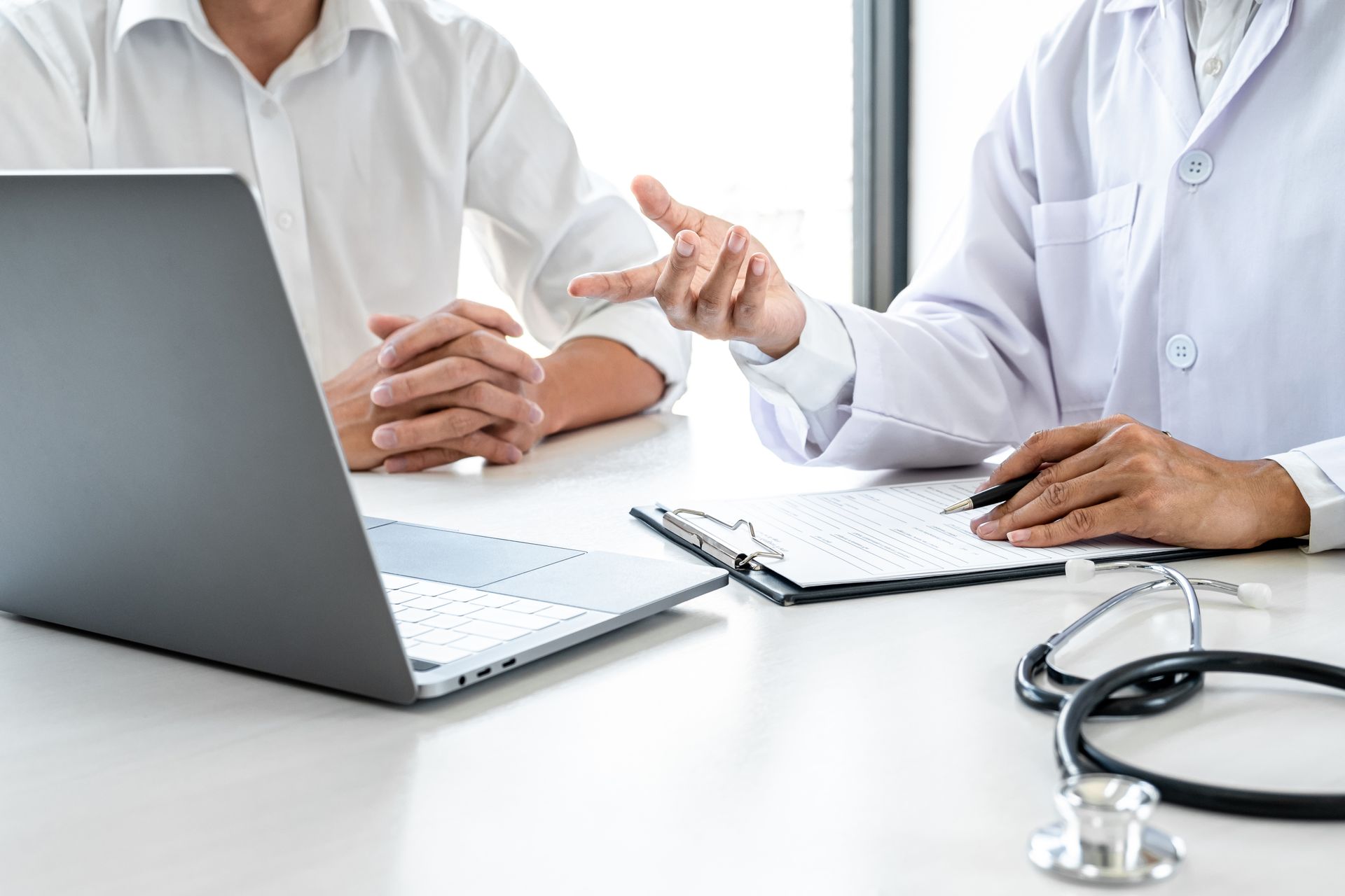 Un medico parla con un paziente mentre utilizza un computer portatile.