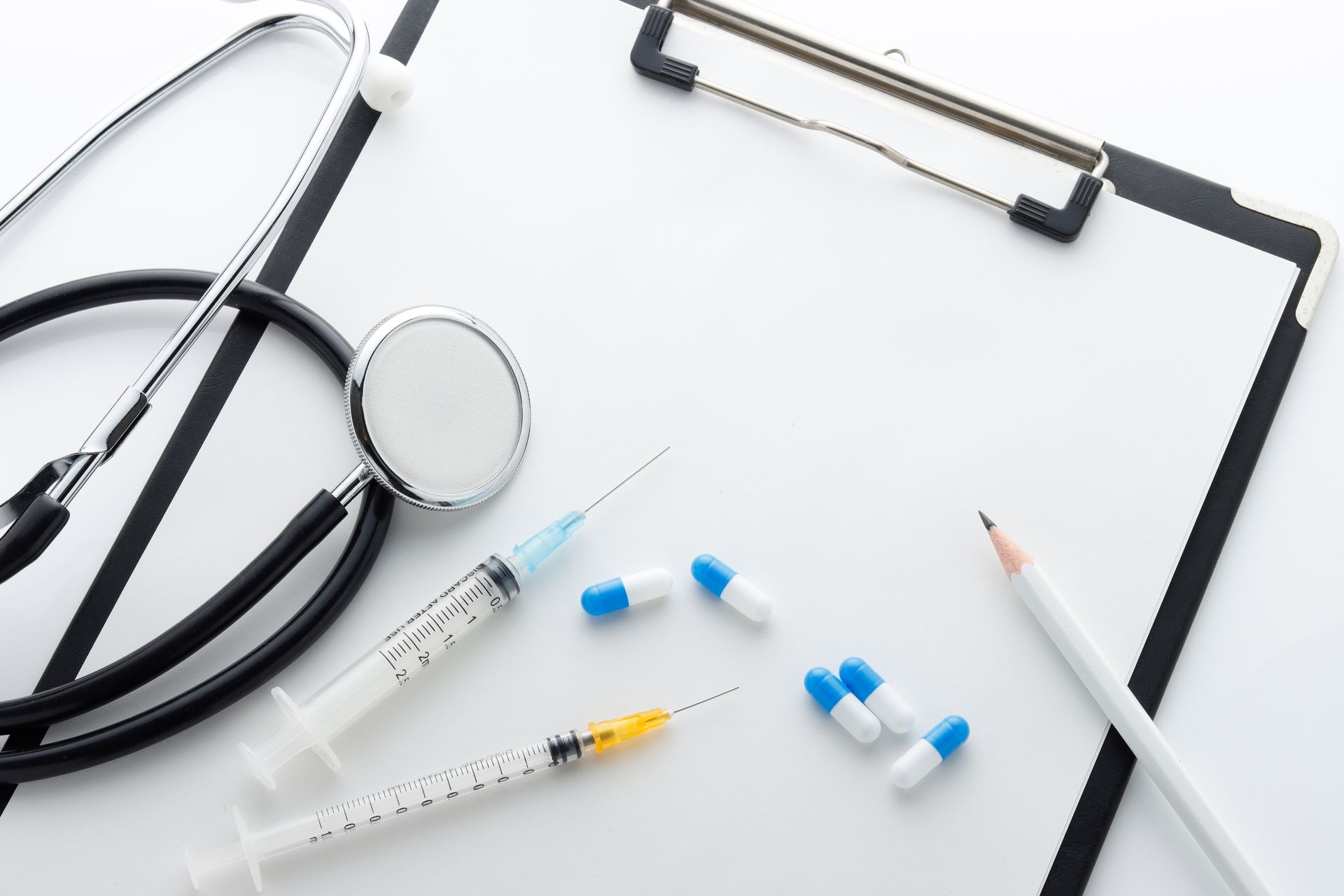 Una lavagna con uno stetoscopio, una siringa, delle pillole e una matita.
