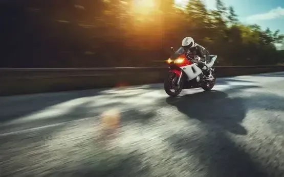 Un hombre va conduciendo una motocicleta por una carretera.