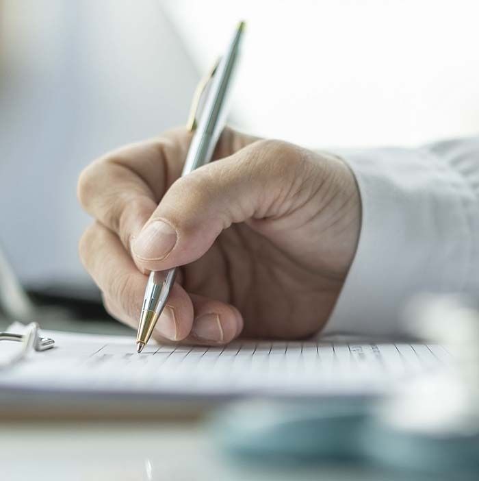 Una persona está escribiendo en un trozo de papel con un bolígrafo.