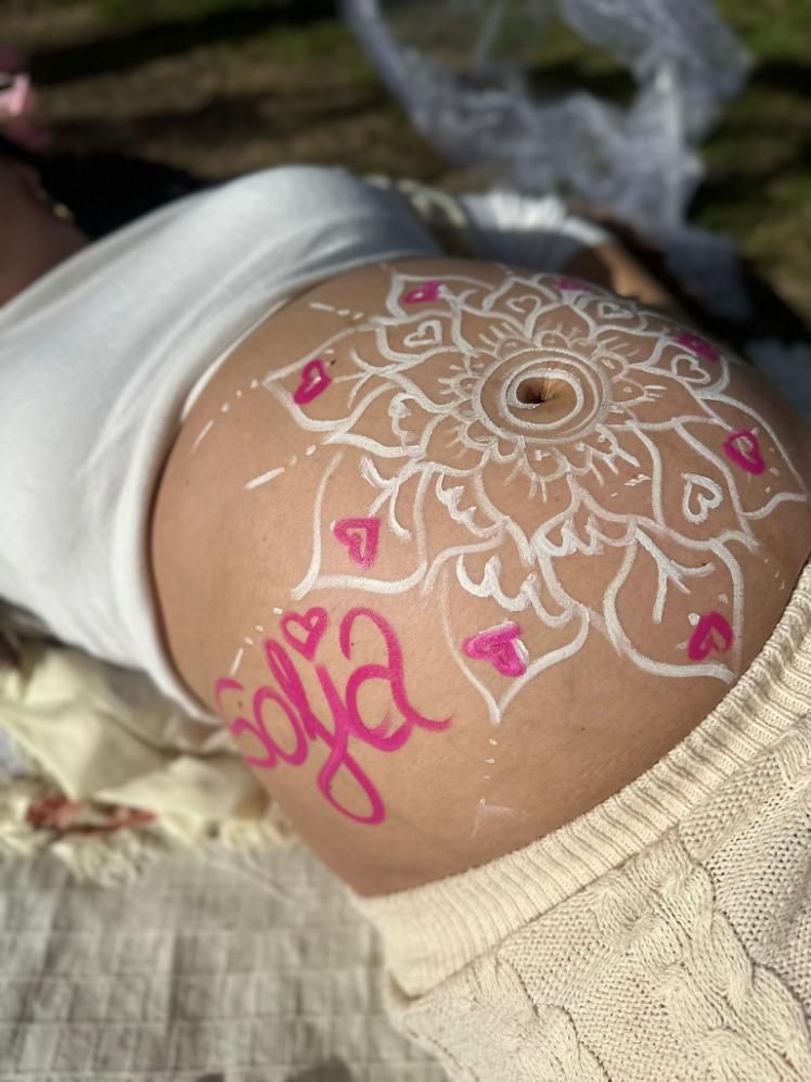 Barriga de embarazada con diseño de mandala blanco y rosa y el nombre 