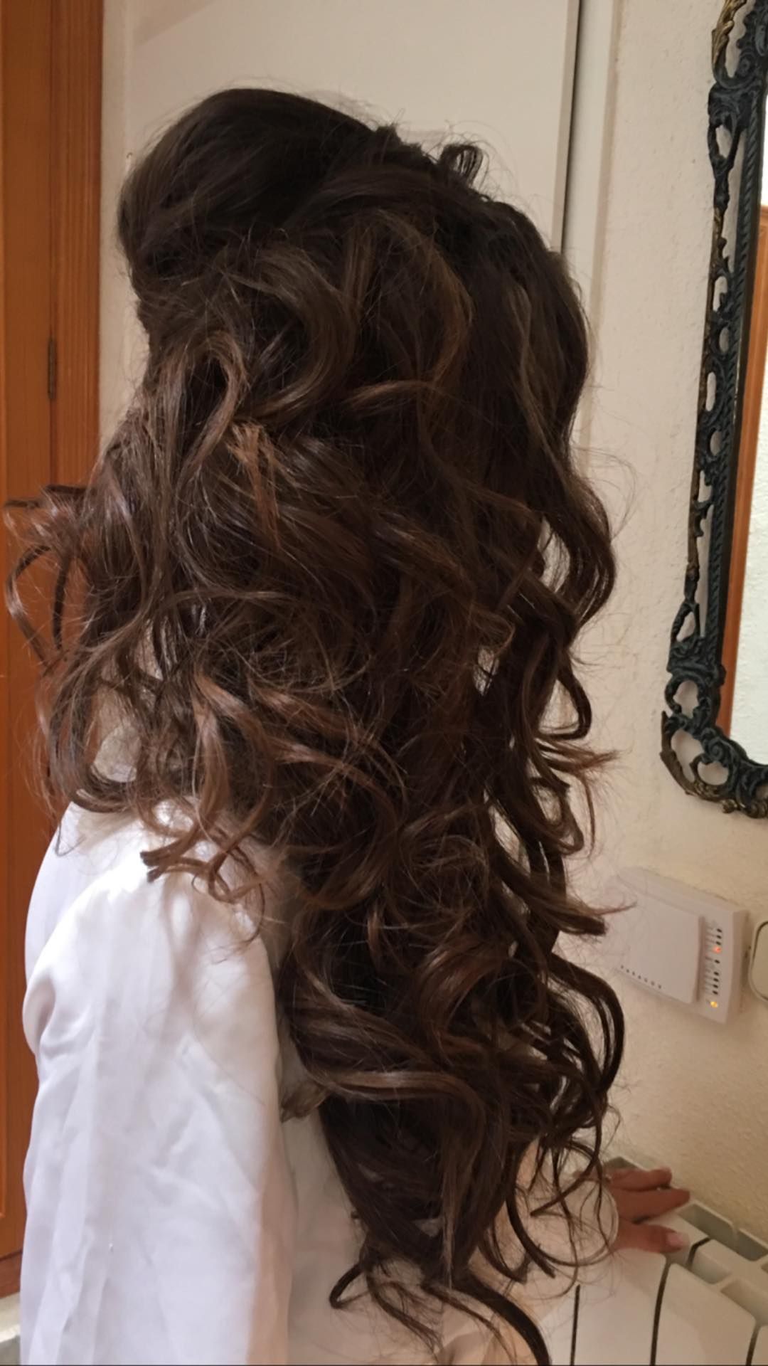 Cabello oscuro y rizado peinado hacia arriba, en cascada, cerca de un espejo.
