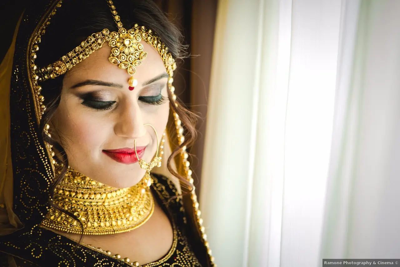 Mujer con joyas de boda de oro adornadas, mirando hacia abajo.