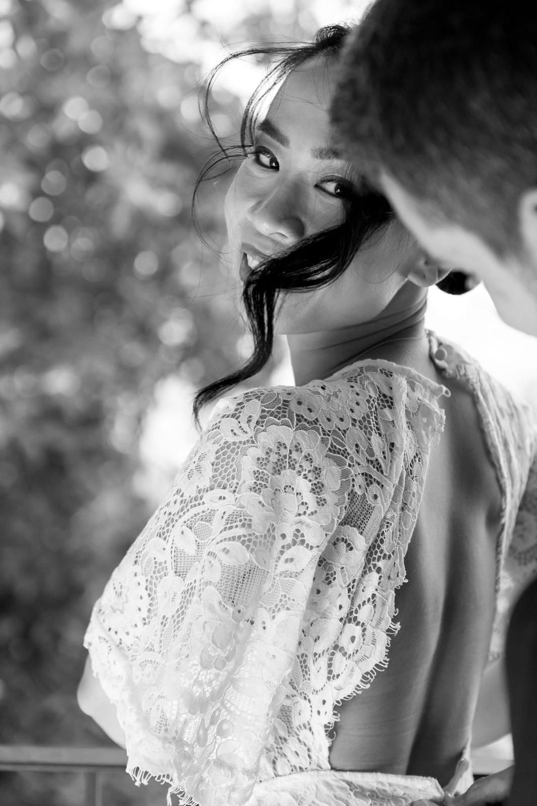 Mujer con vestido de encaje sonríe, mirando por encima del hombro.