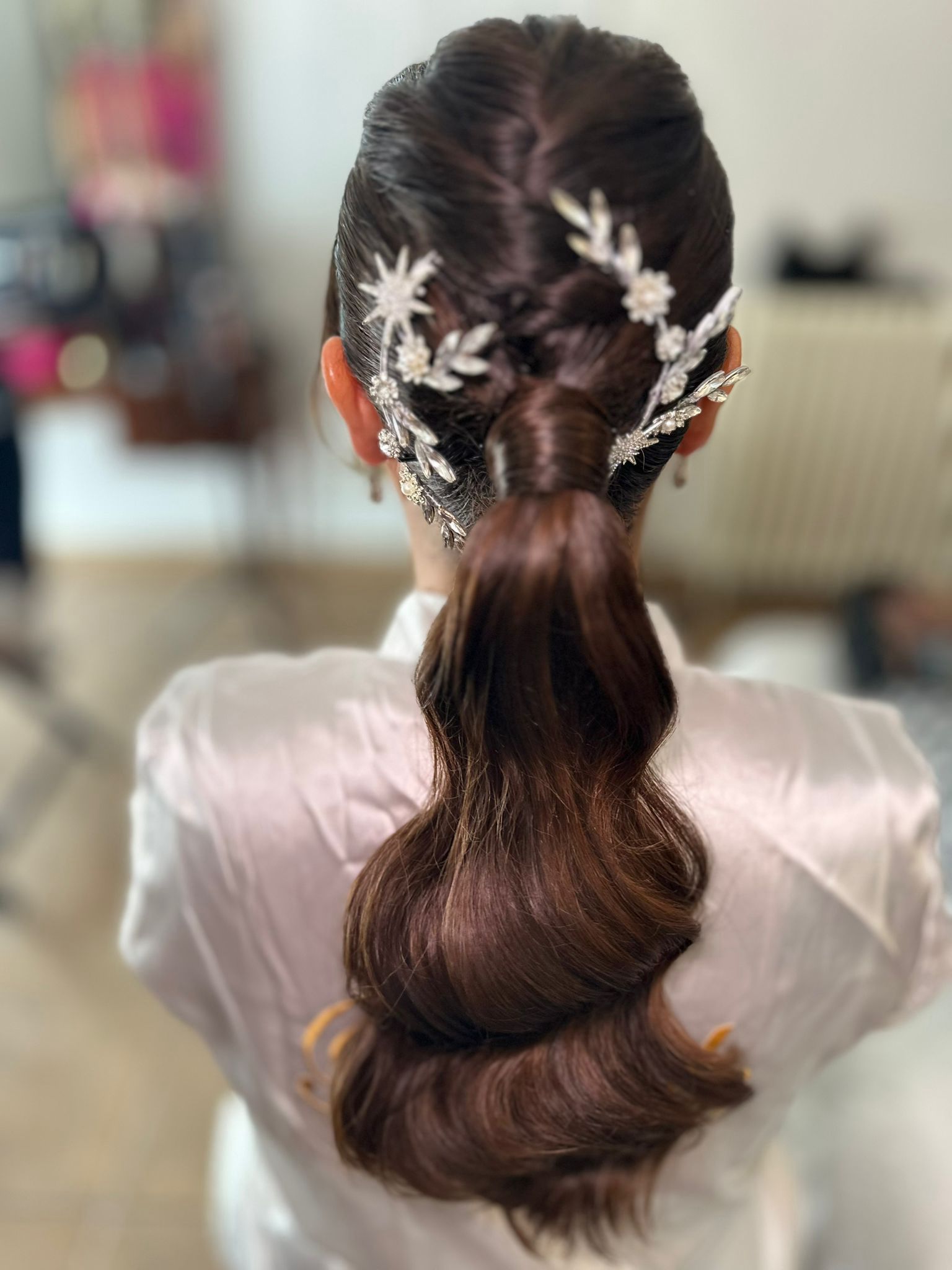 Mujer con peinado recogido tiene el cabello peinado mientras usa un vestido blanco.