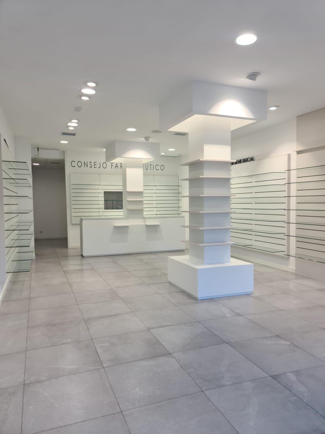 Una farmacia vacía con un mostrador blanco y estantes.
