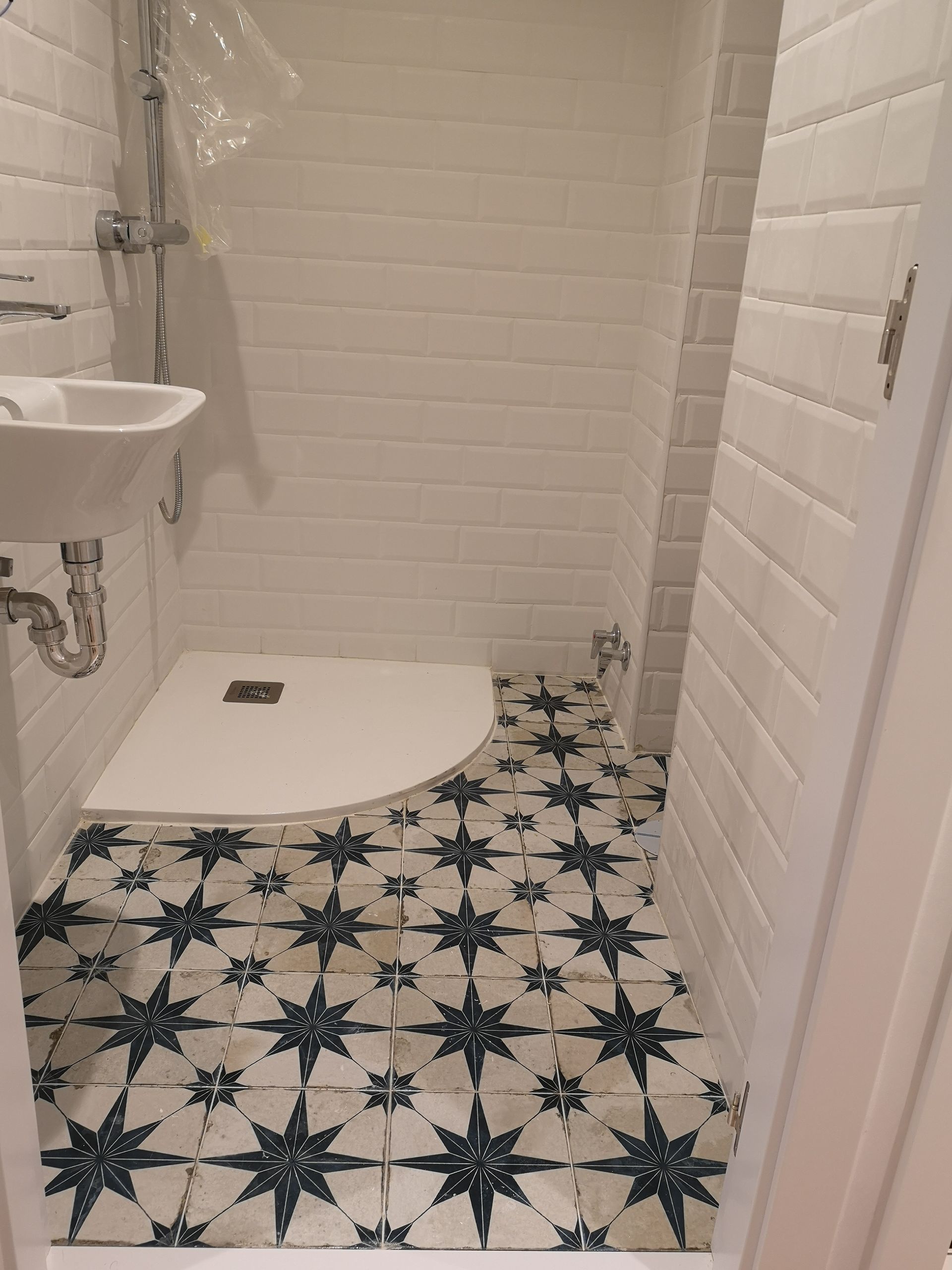 Un baño con lavabo, ducha y suelo de baldosas en forma de estrella.