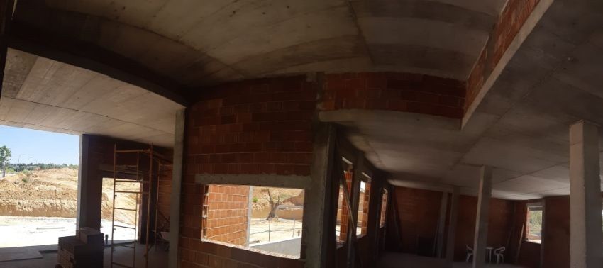 Interior de un edificio en construcción. Se ven paredes de ladrillo rojo y techos de hormigón