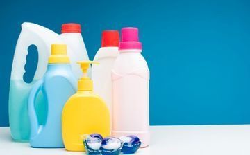 Surtido de botellas y cápsulas de detergente para ropa de colores sobre un fondo azul.