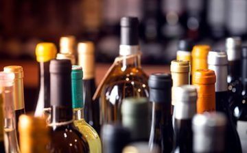 Botellas de vino variadas, con sus corchos y etiquetas, dispuestas en filas sobre una barra o mostrador de degustación.